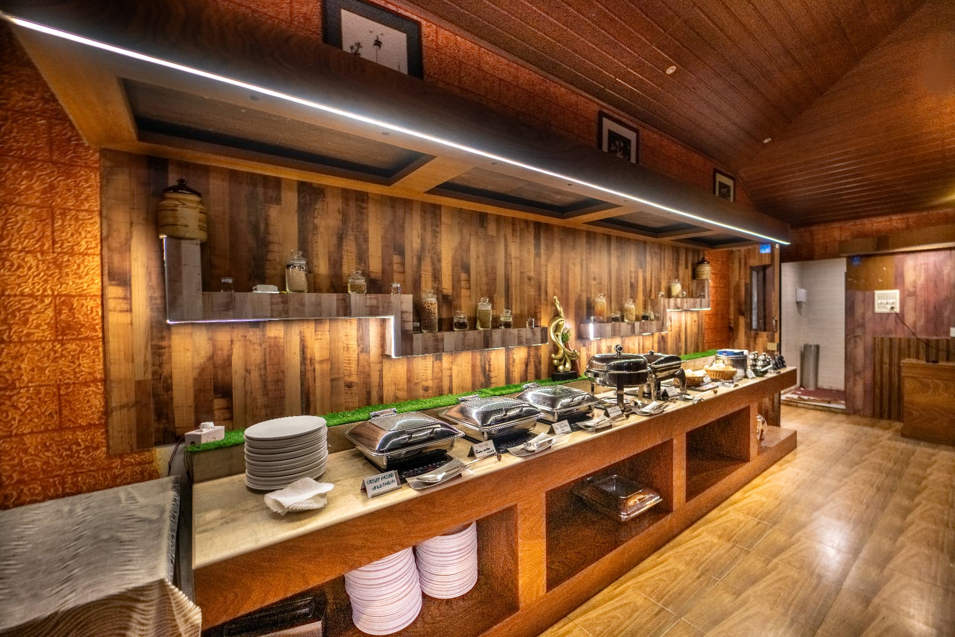 Buffet counter at the in-house restaurant of Grand Valley Resort, Munnar, under a wooden vaulted ceiling